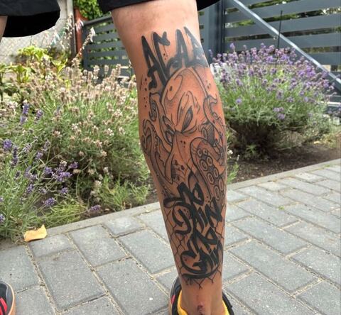 Tatuaż graficzny z ośmiornicą i napisem w stylu graffiti na łydce – tatuaż liternicy Gniezno