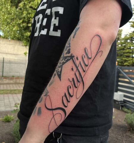 Tatuaż napisowy Sacrifice z gwiazdą na przedramieniu – tatuaż lettering męski Gniezno